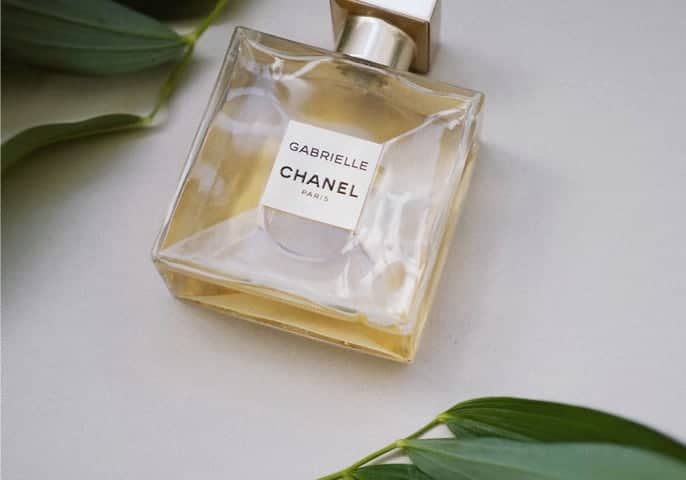 Perfume on a wooden table and green leaf decoration around it